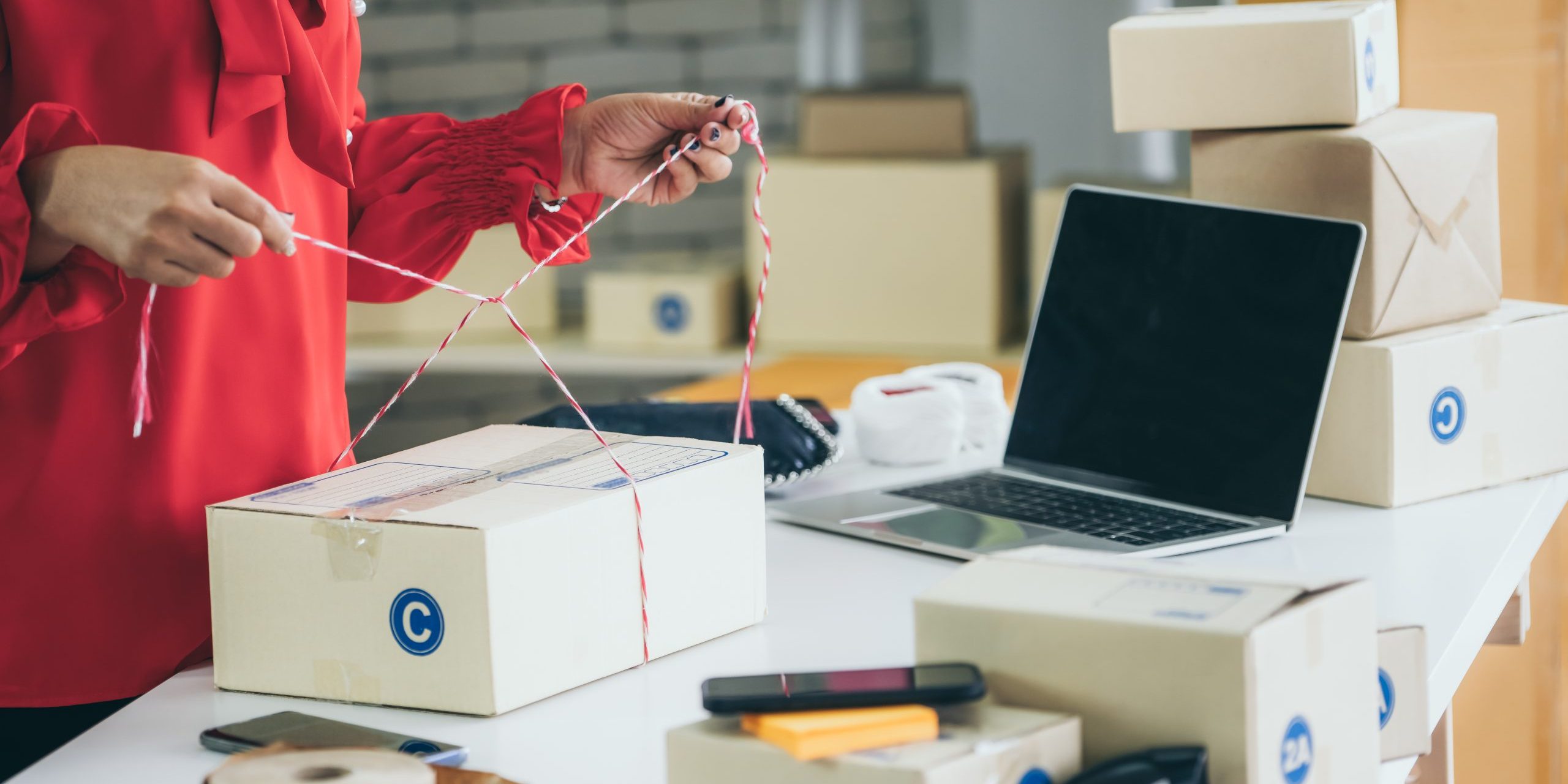 Online seller works at home office and packs shipping delivery box to customer.