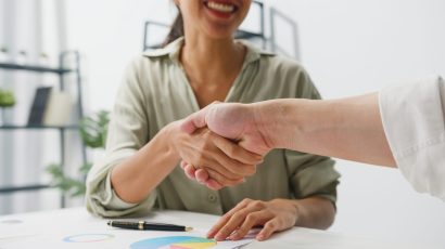 Multiracial group of young creative people in smart casual wear Multiracial group of young creative people in smart casual wear discussing business shaking hands together and smiling while sitting in modern office. Partner cooperation, coworker teamwork concept.